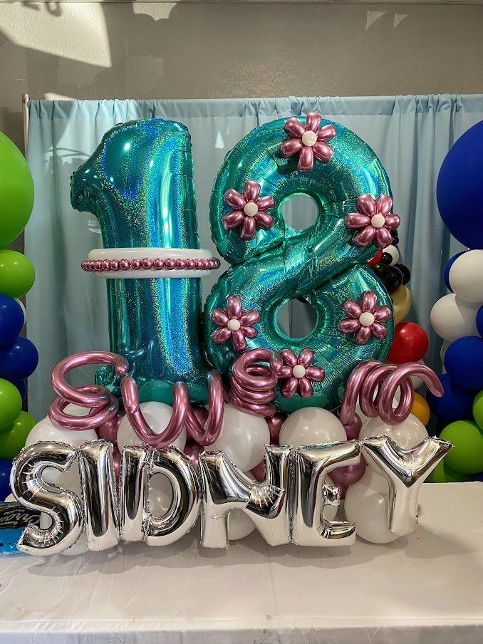 A bouquet of balloons with the number 18 and the name sidney on a table.
