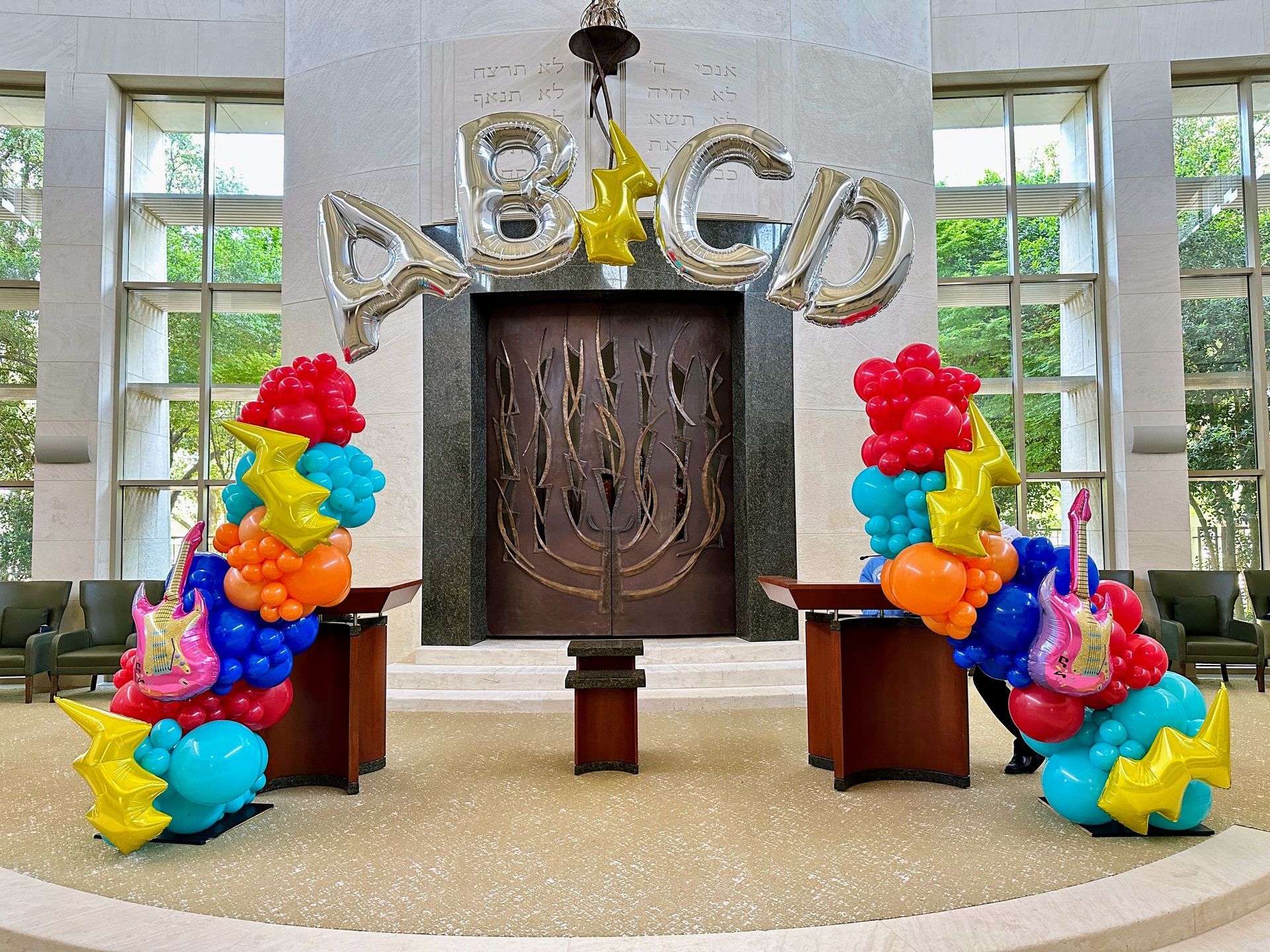 A helium balloon arch with foil balloon letters and colorful balloons and accents.
