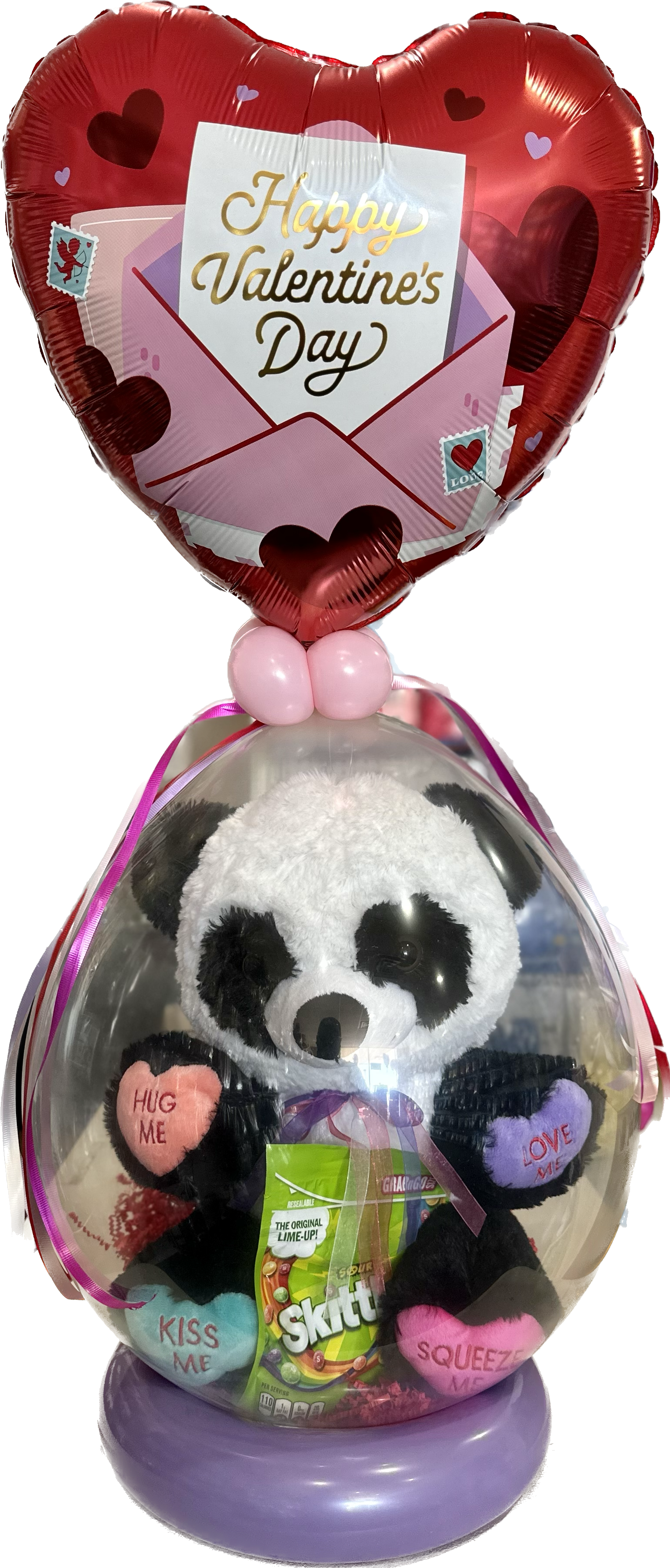A stuffed panda is sitting inside of a heart shaped balloon.