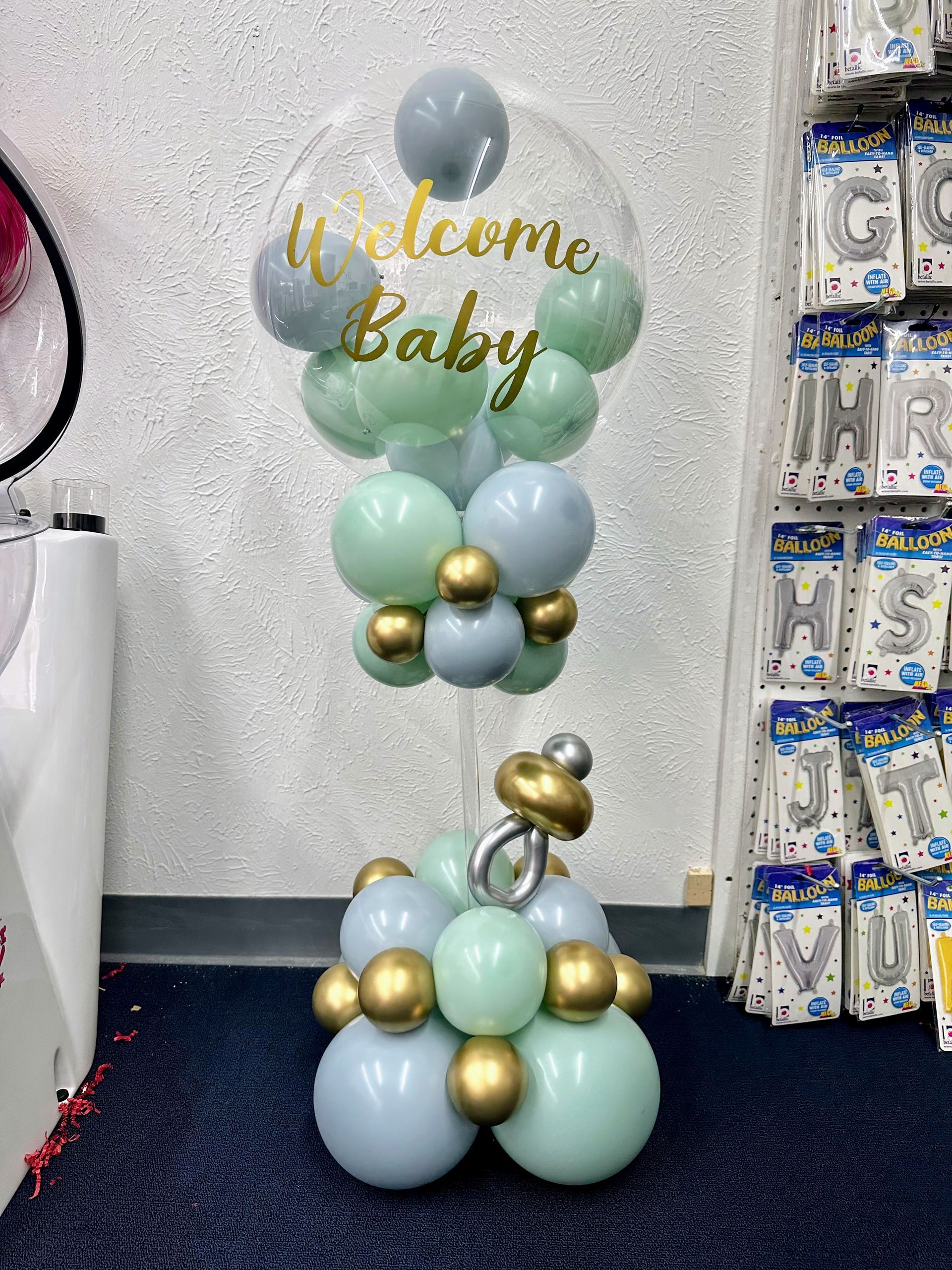 A baby shower balloon arrangement with a welcome baby balloon in the middle.