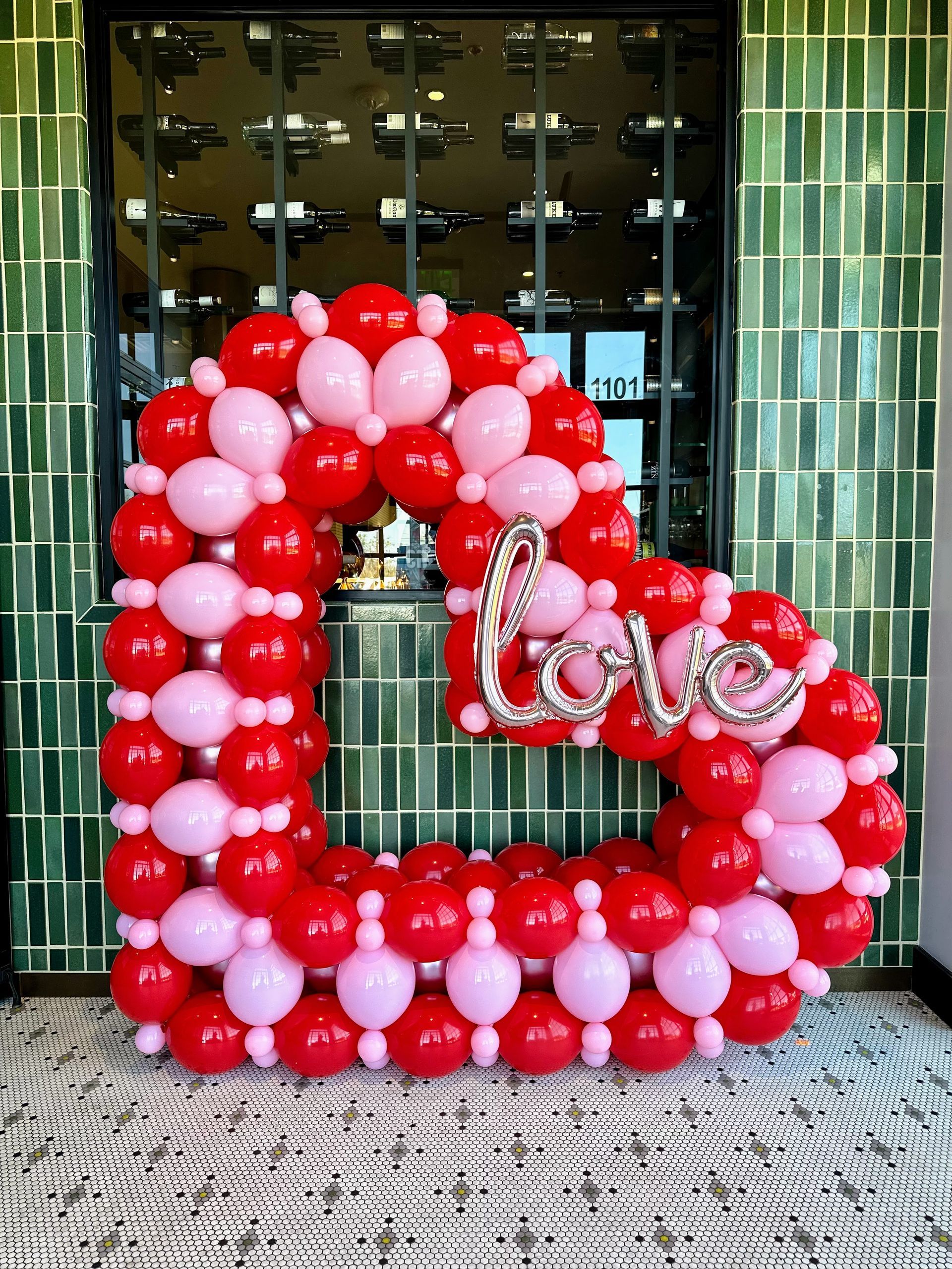 A heart made of red and pink balloons with the word love on it