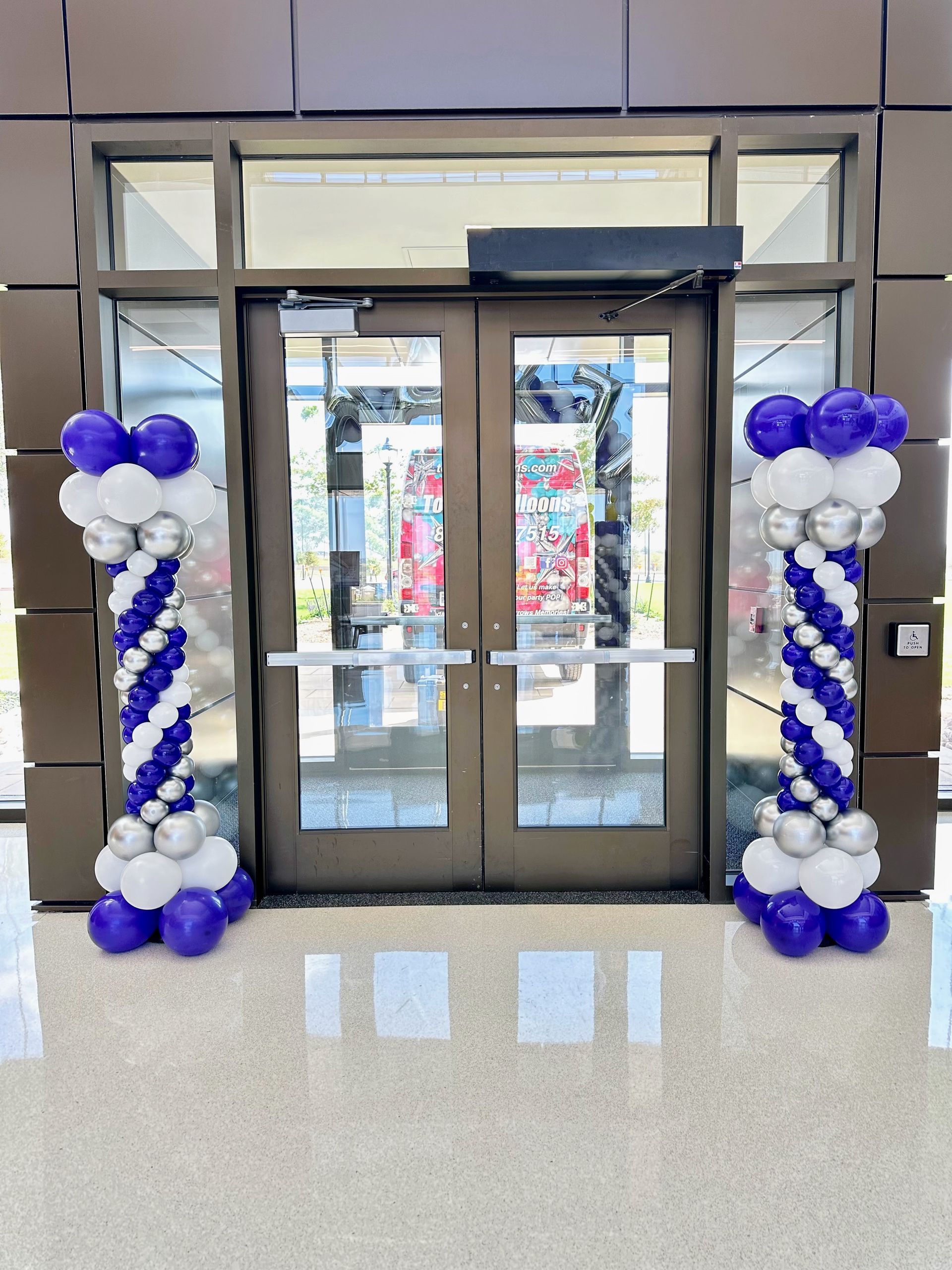 A doorway with purple and white balloons in front of it.