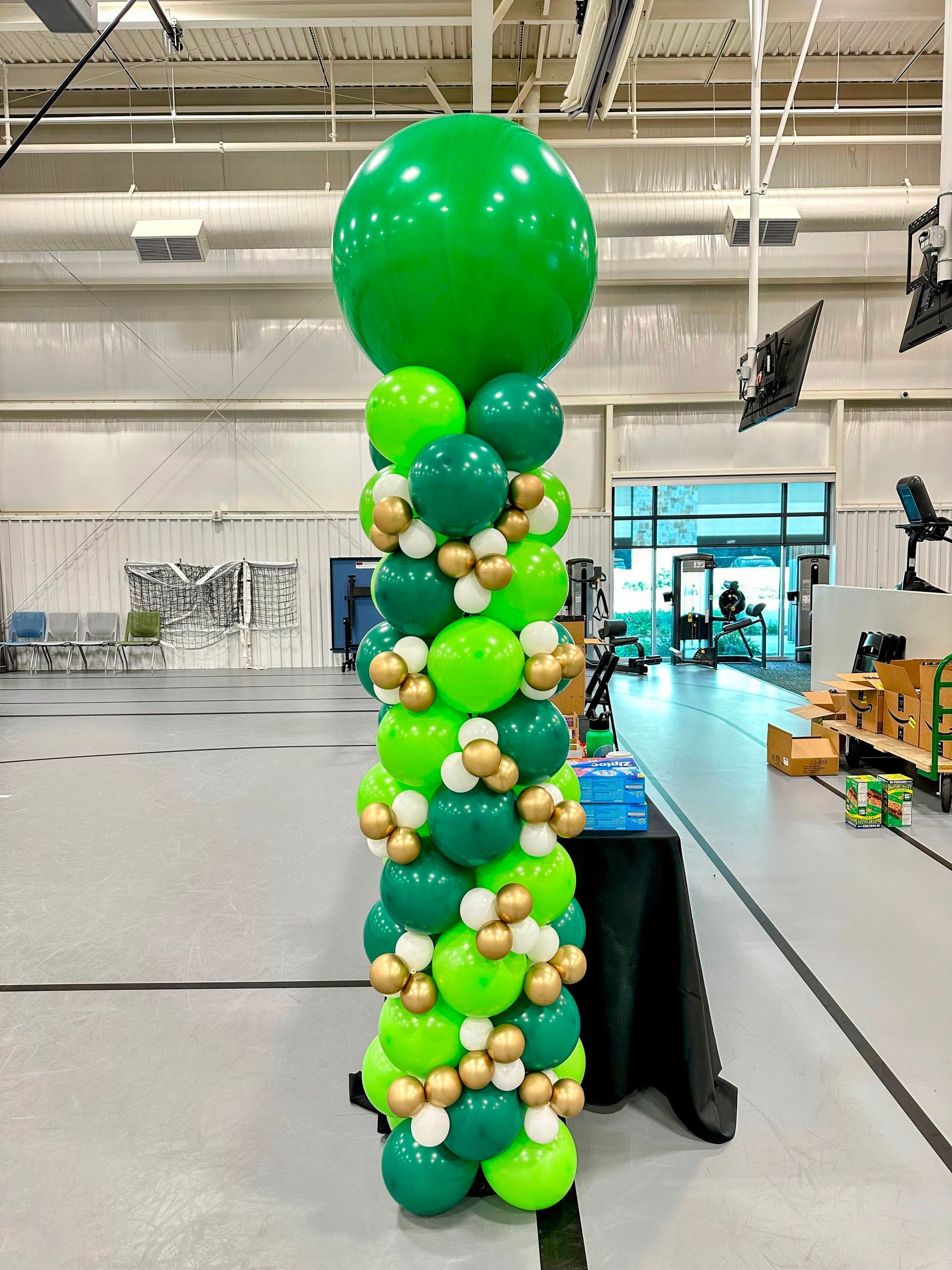 A row of green and gold balloons are stacked on top of each other in a room.