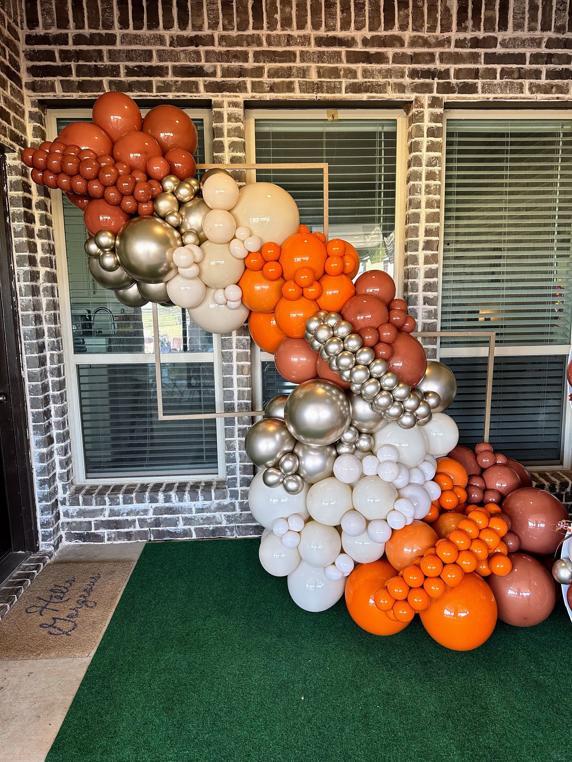 A bunch of balloons are sitting in front of a brick building.