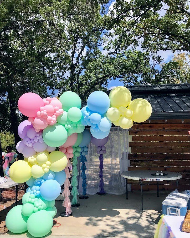 A bunch of balloons are sitting on the ground in front of a wooden wall.