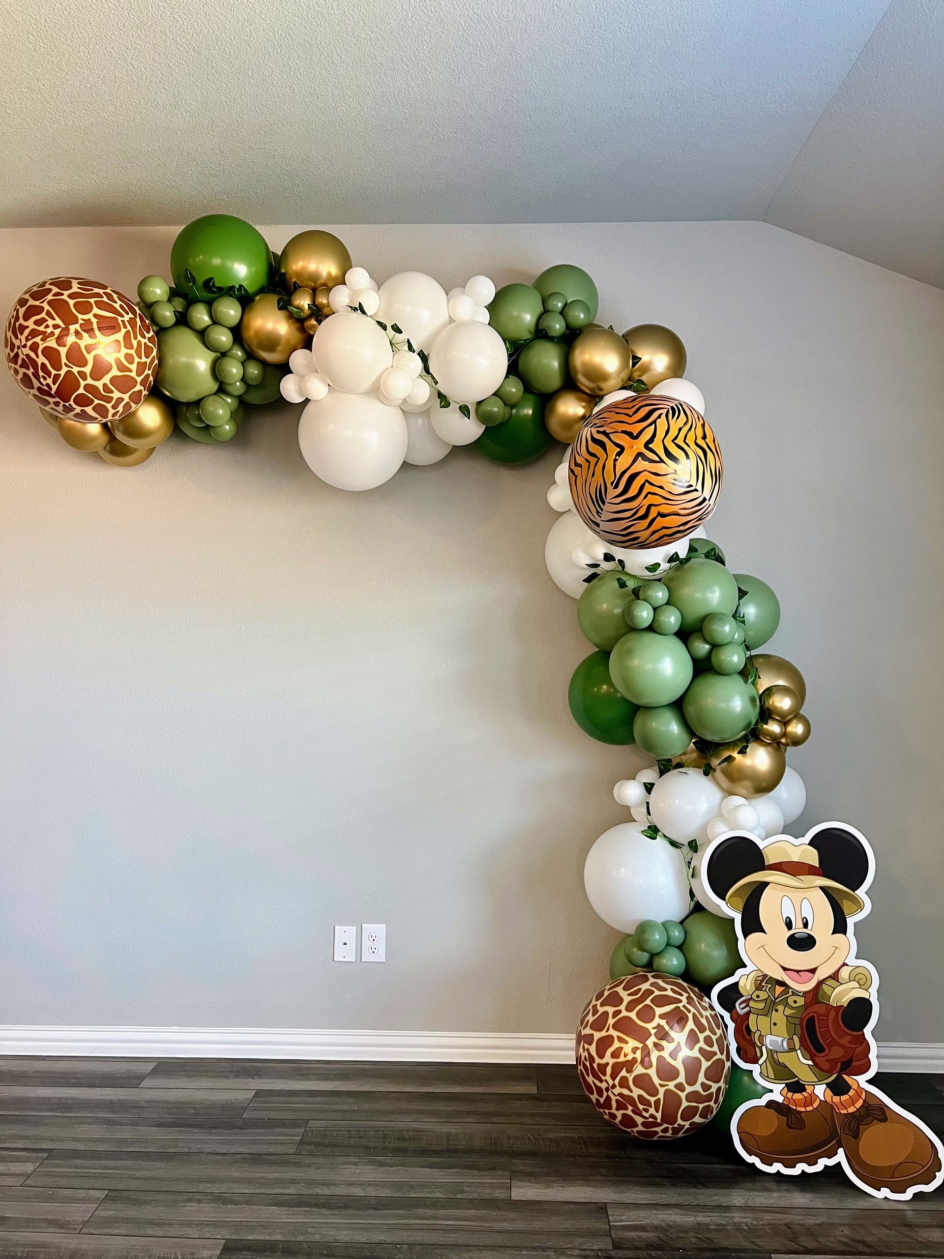 A room with balloons and a picture of mickey mouse on the wall.