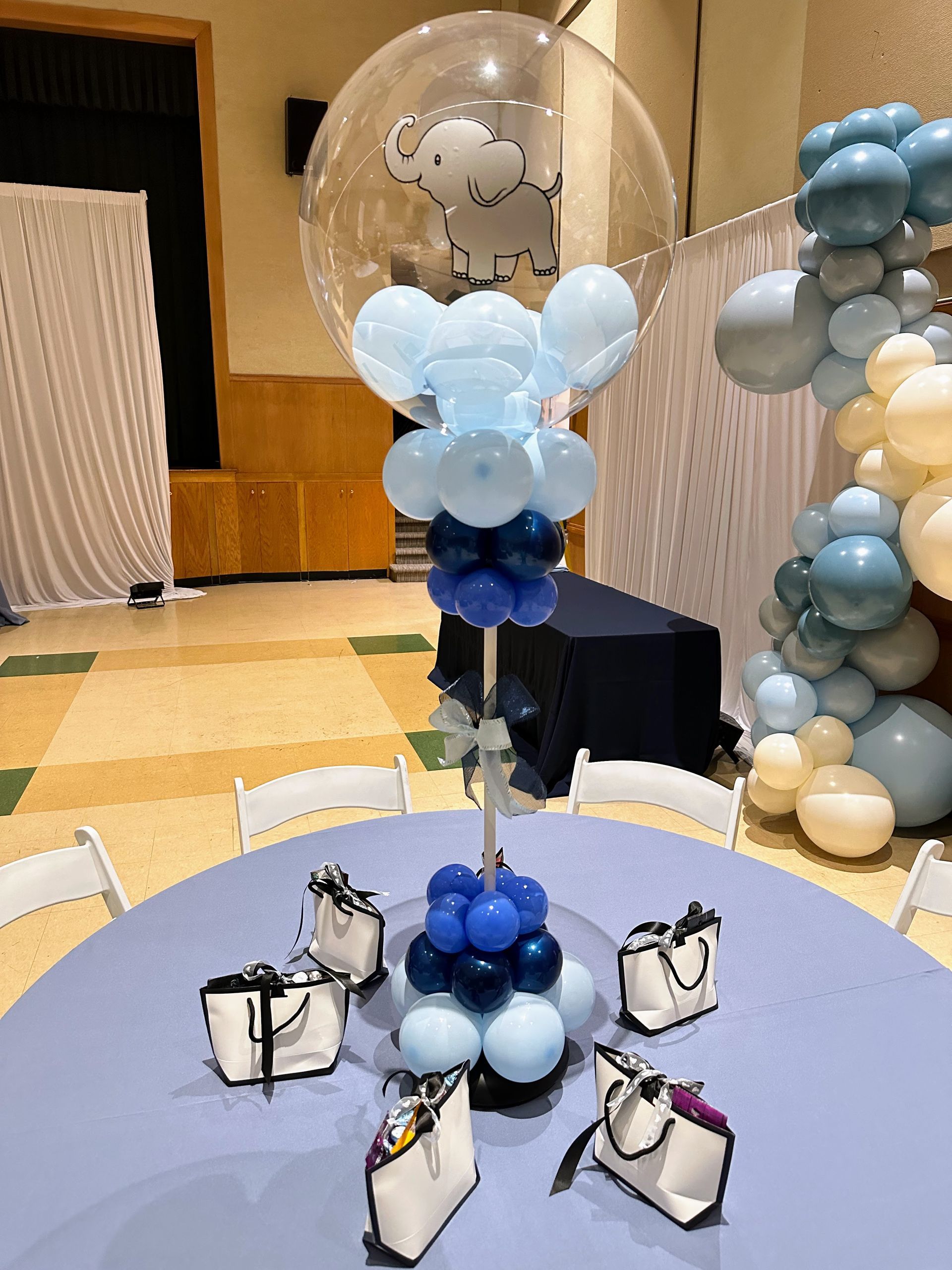 A table decorated with balloons and handbags for a baby shower.