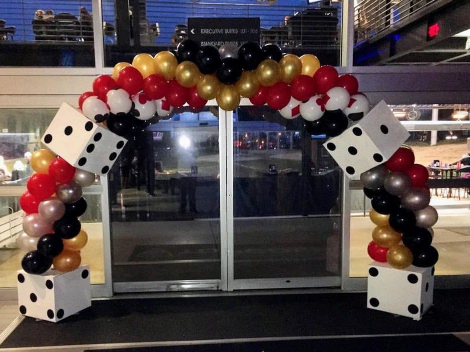 A balloon arch with dice in the middle of it
