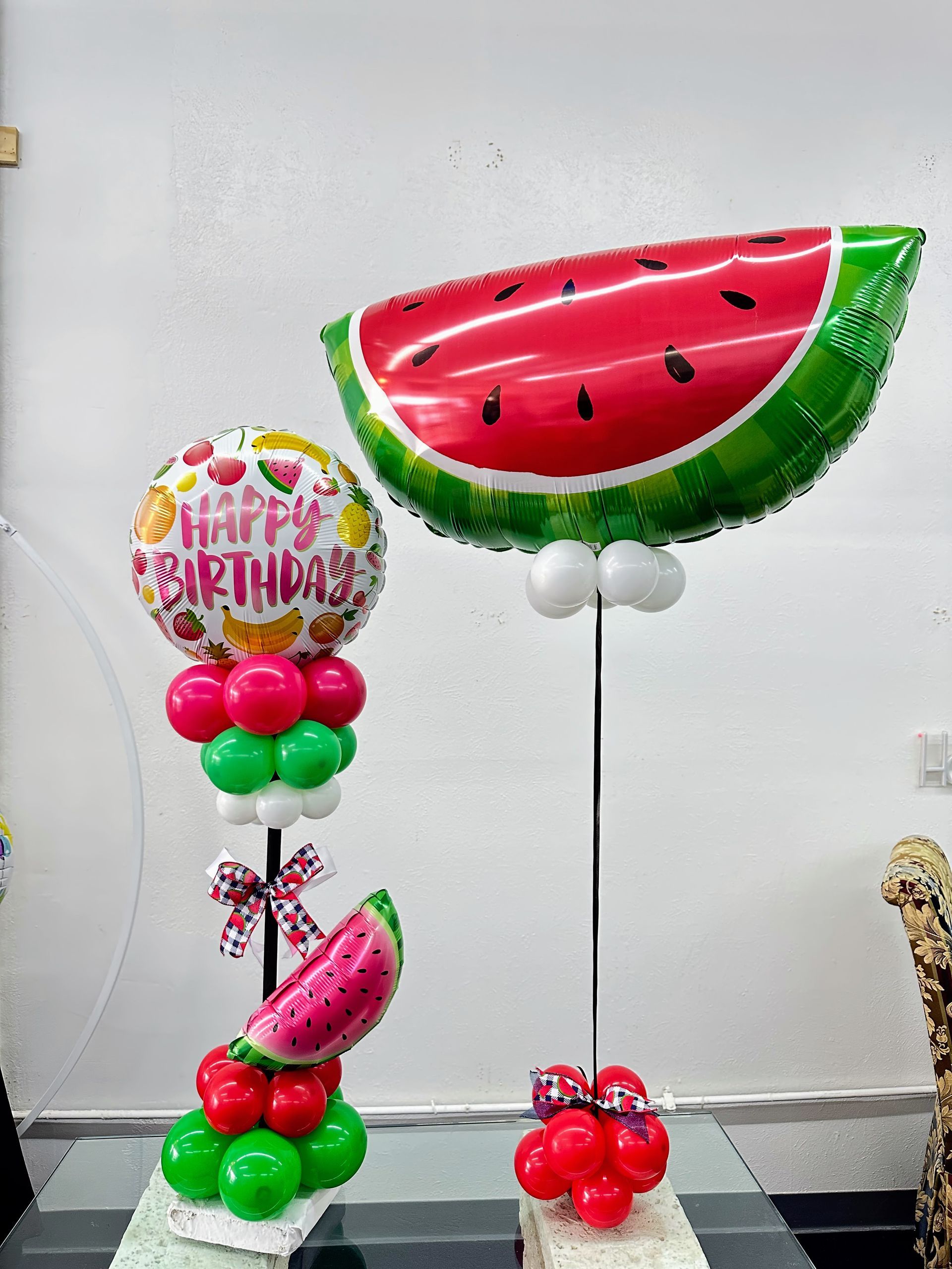Two watermelon shaped balloons are sitting on top of a table.