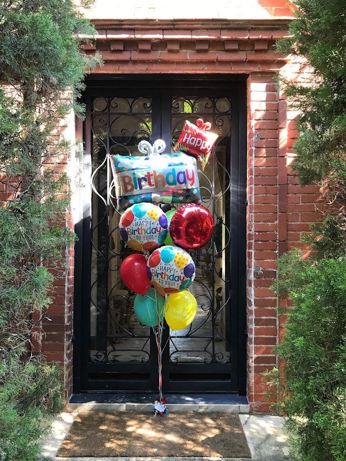 A bunch of birthday balloons are sitting in front of a door.