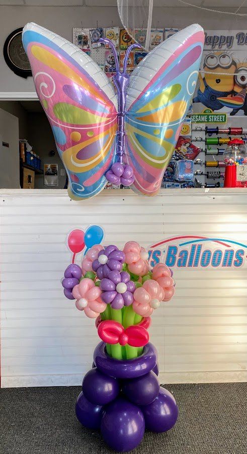 A butterfly shaped balloon is sitting on top of a bunch of balloons.