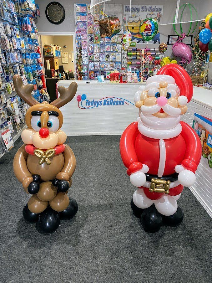 A reindeer and santa claus made out of balloons are standing next to each other in a store.