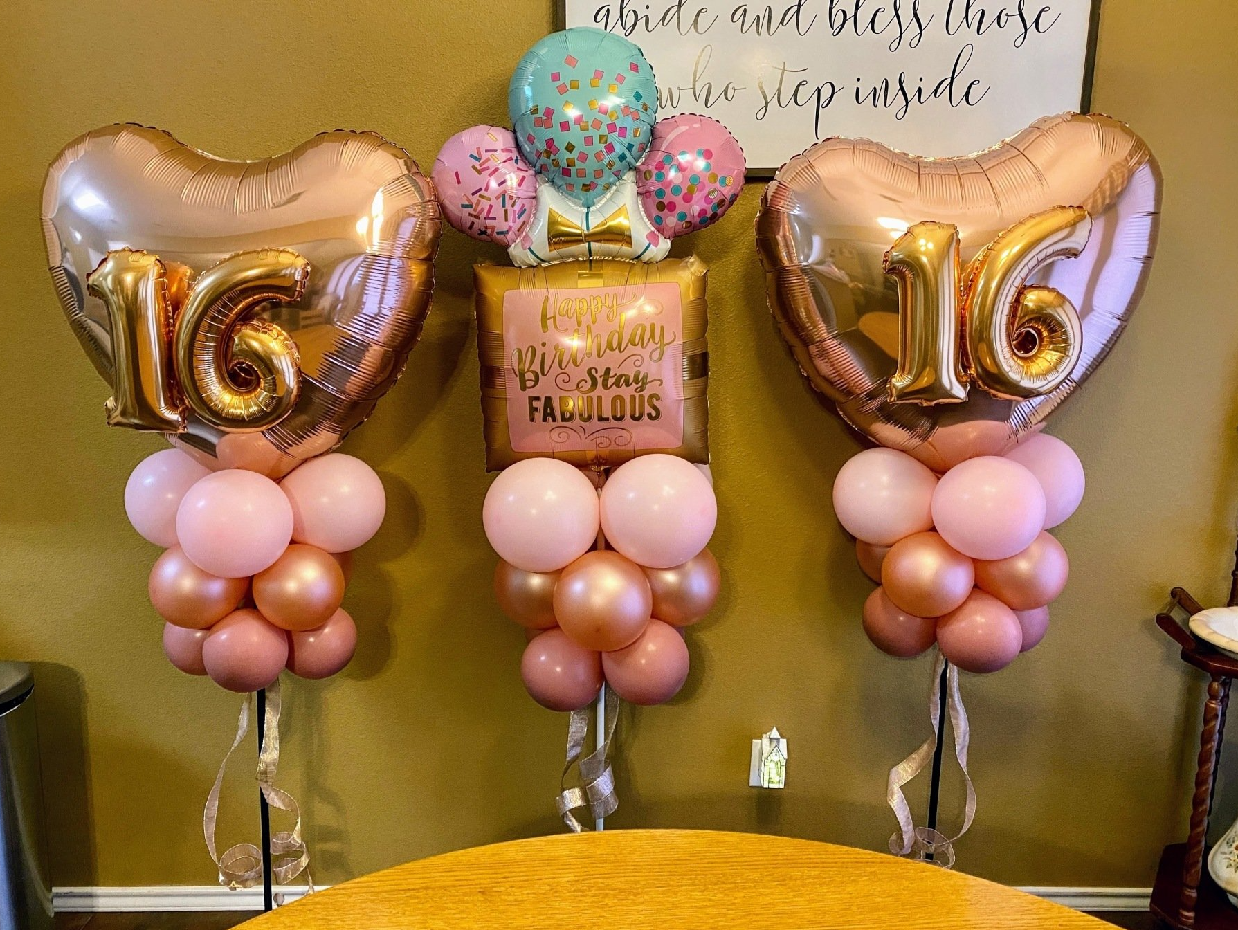 Three heart shaped balloons with the number 16 on them are sitting on top of a table.