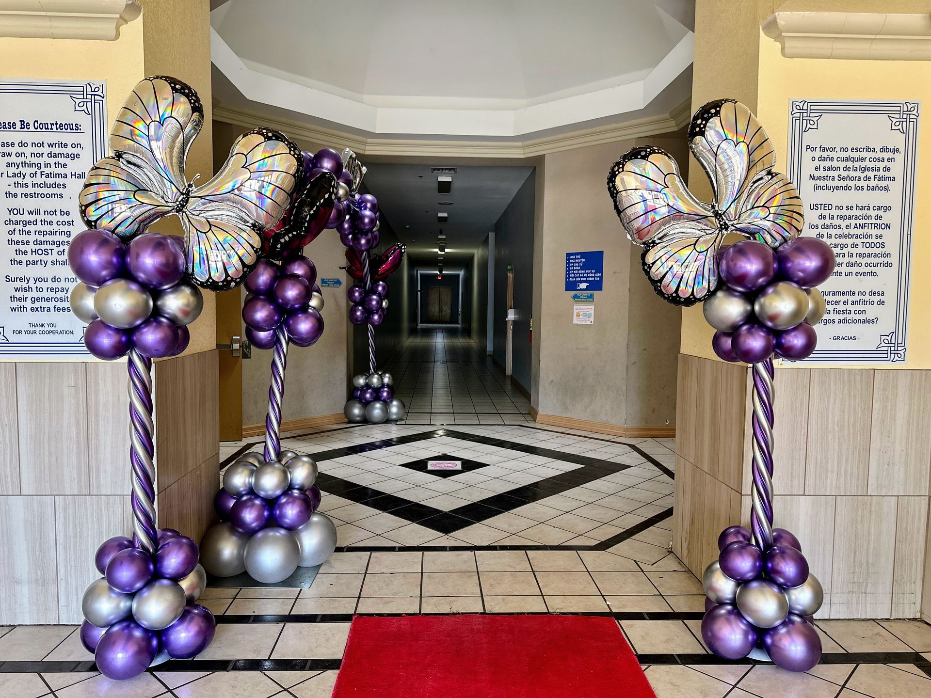A hallway with purple and silver balloons and a red carpet
