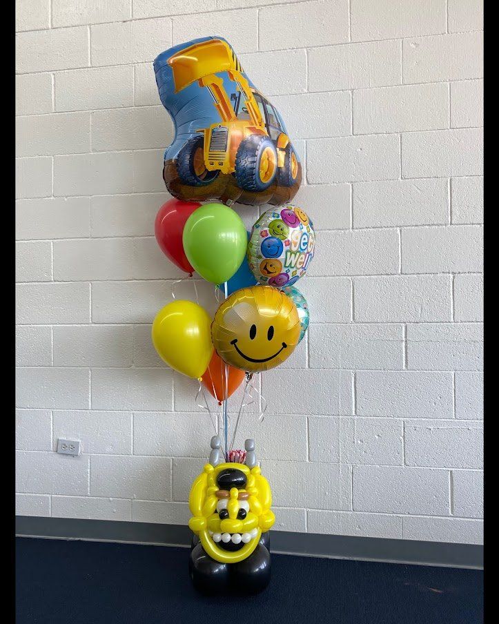 A bunch of balloons are sitting on a table in front of a brick wall