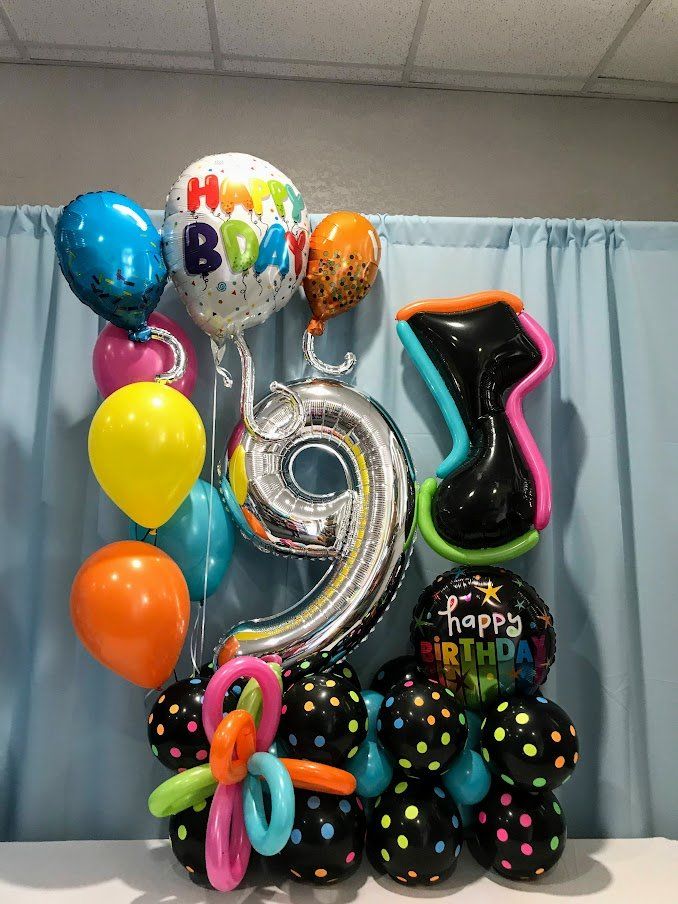 A bunch of balloons are sitting on a table in front of a blue curtain.