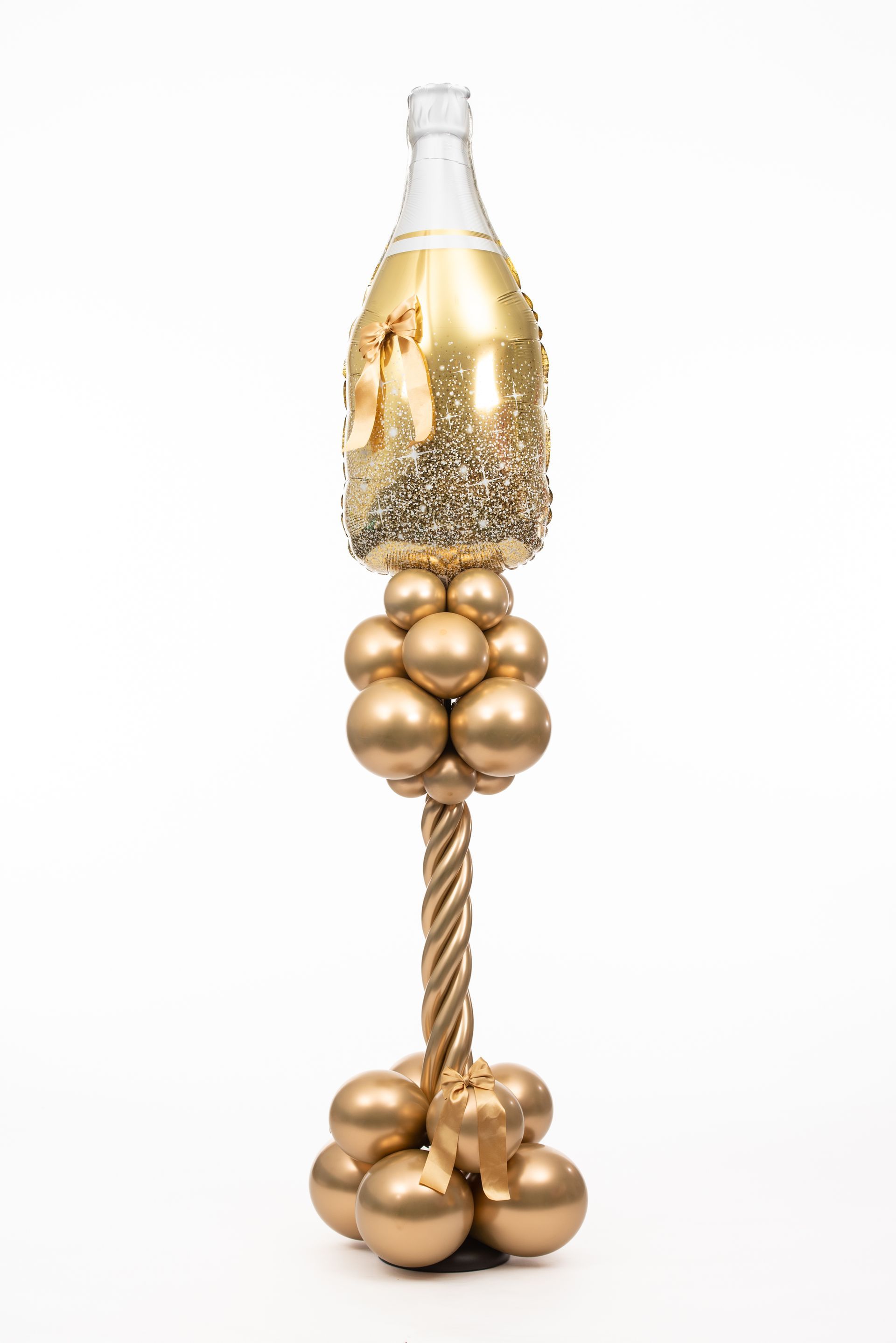 A bottle of champagne is sitting on top of a bunch of gold balloons.