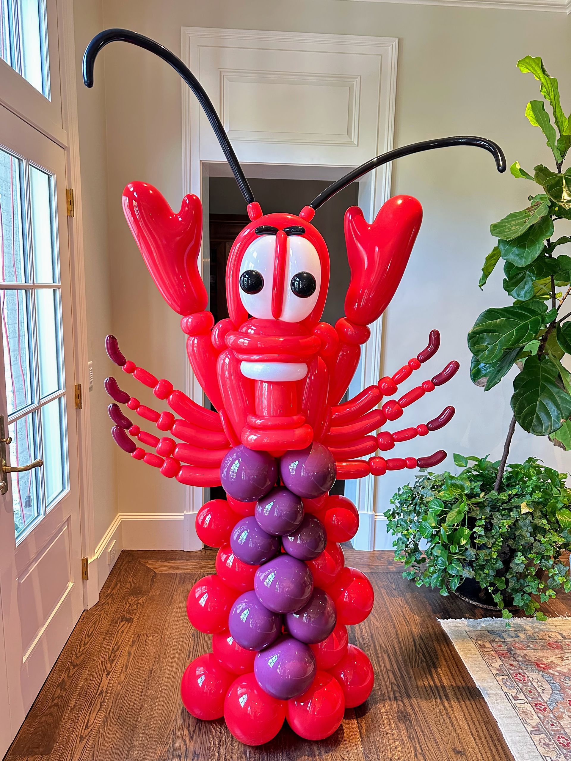 A lobster made out of red and purple balloons in a hallway.