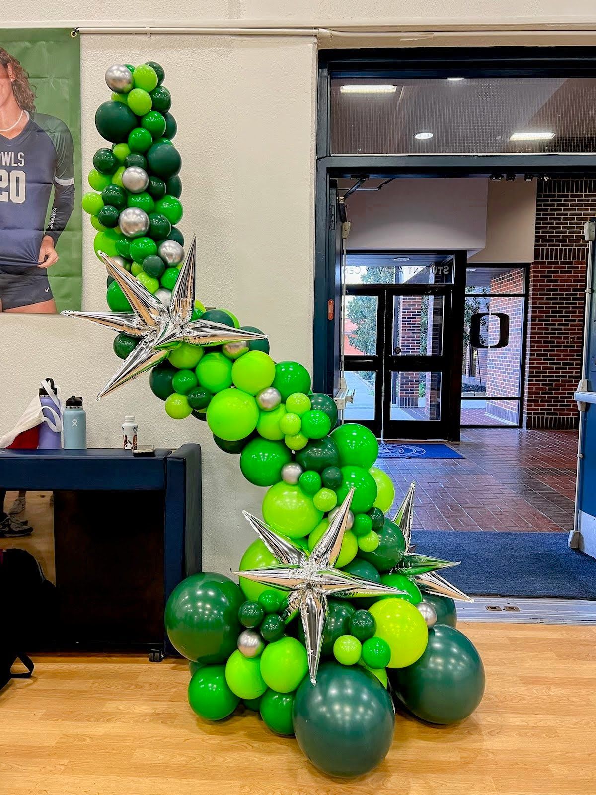 A christmas tree made of green and yellow balloons in a room.