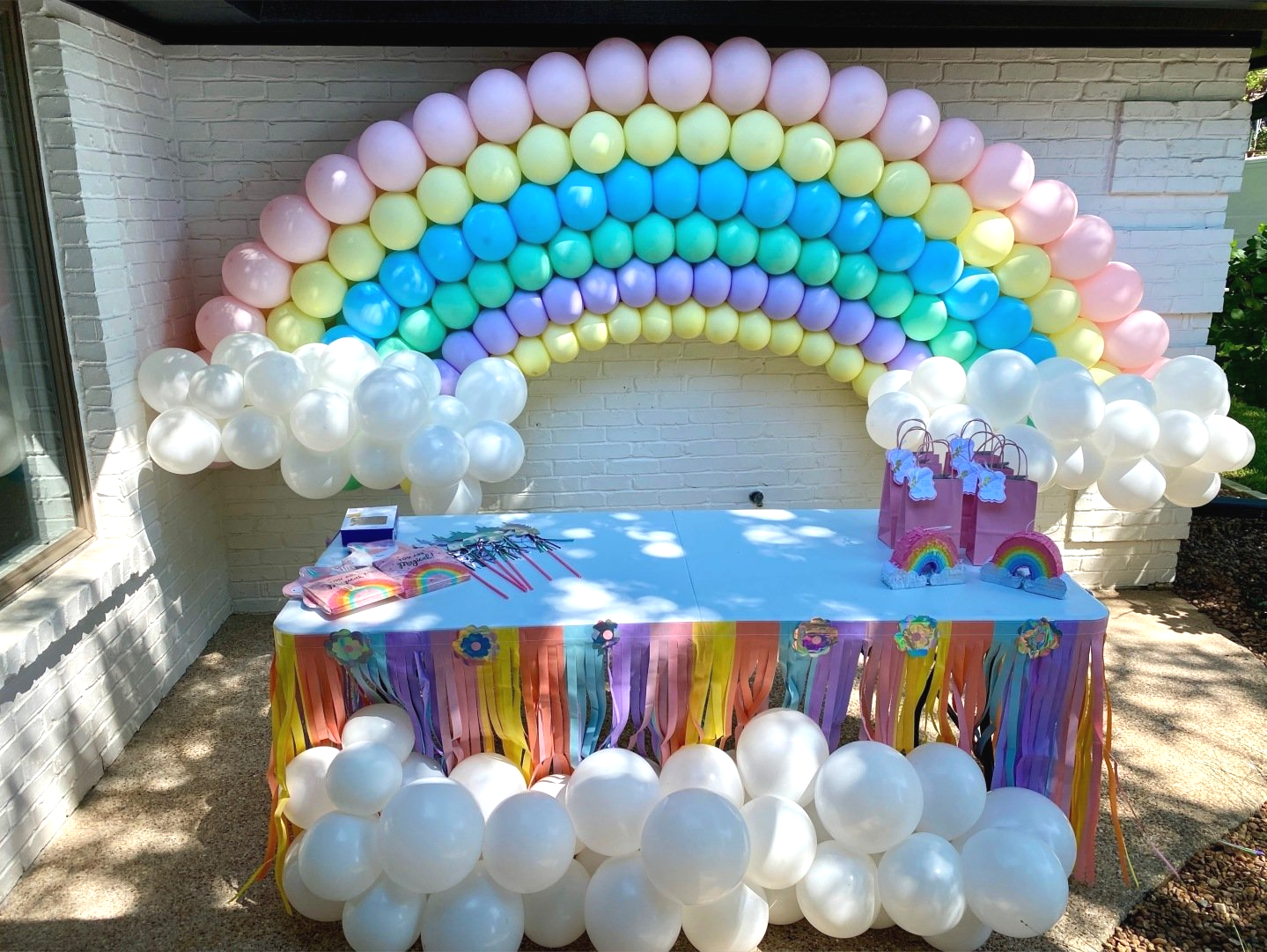 A table is decorated with balloons in the shape of a rainbow.