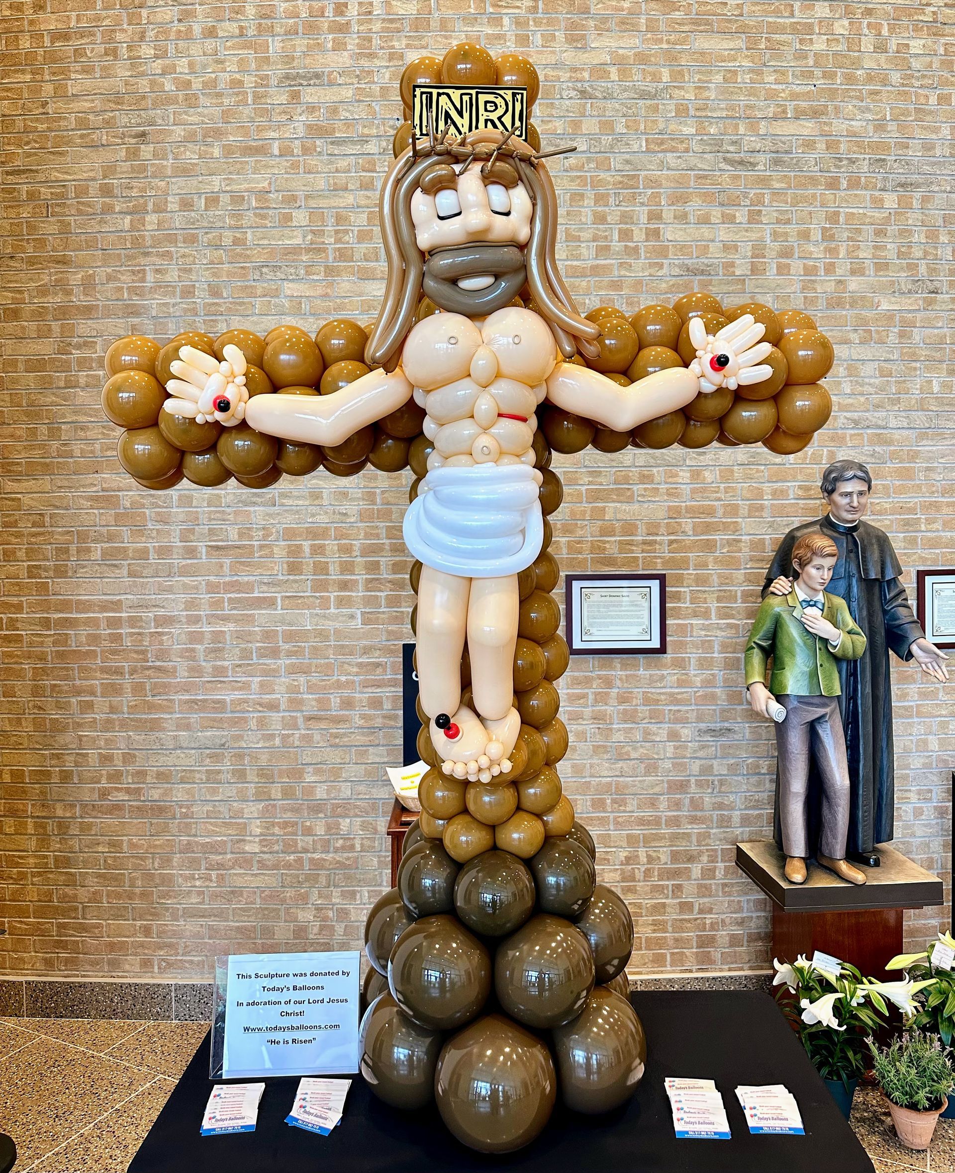 A statue of jesus on a cross made of balloons.