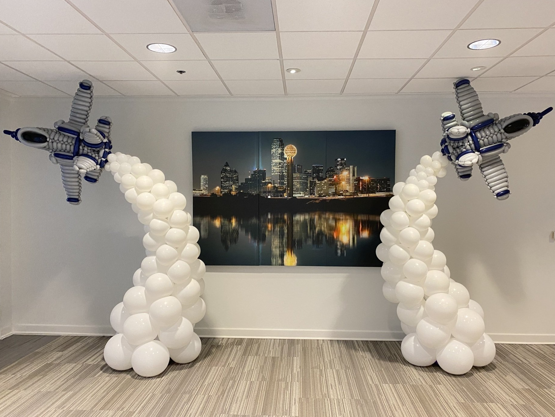 A room filled with balloons and a painting of a city at night.