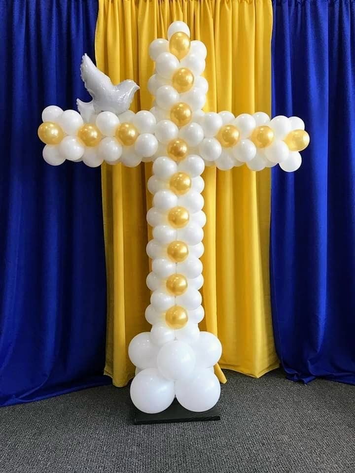 A cross made out of balloons with a dove on top.