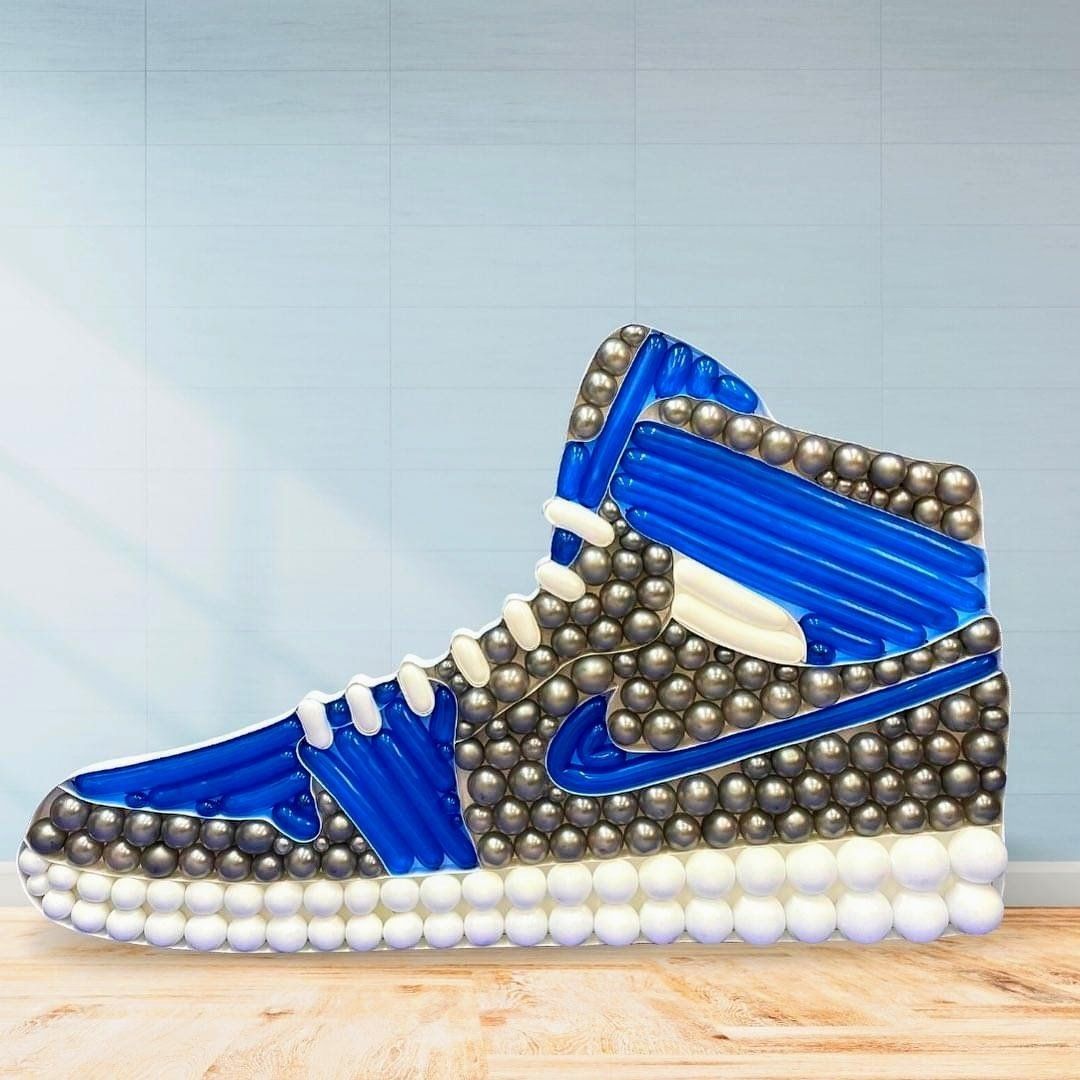 A nike shoe made out of balloons is sitting on a wooden table.