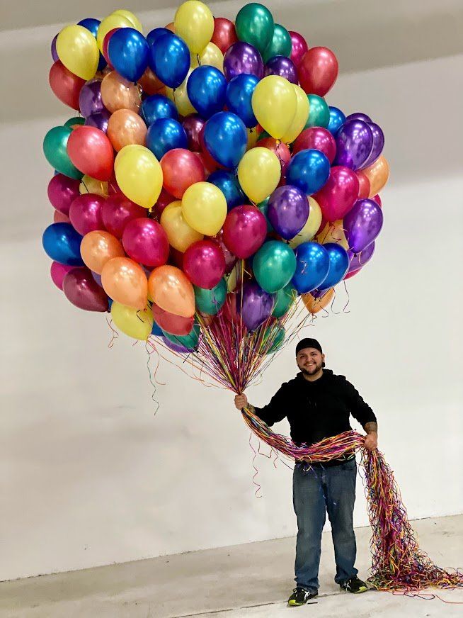A man is holding a bunch of colorful balloons