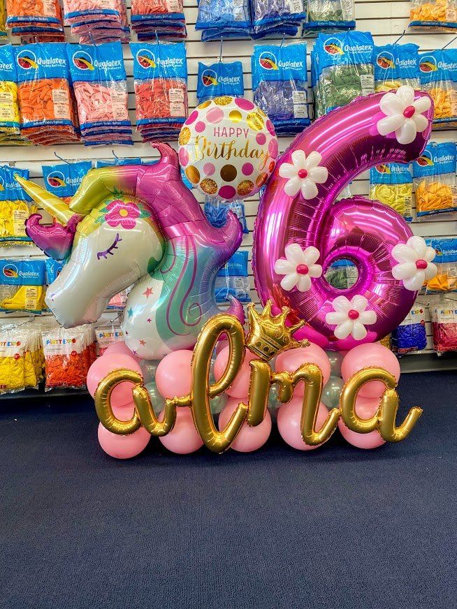A girl is celebrating her sixth birthday with balloons.