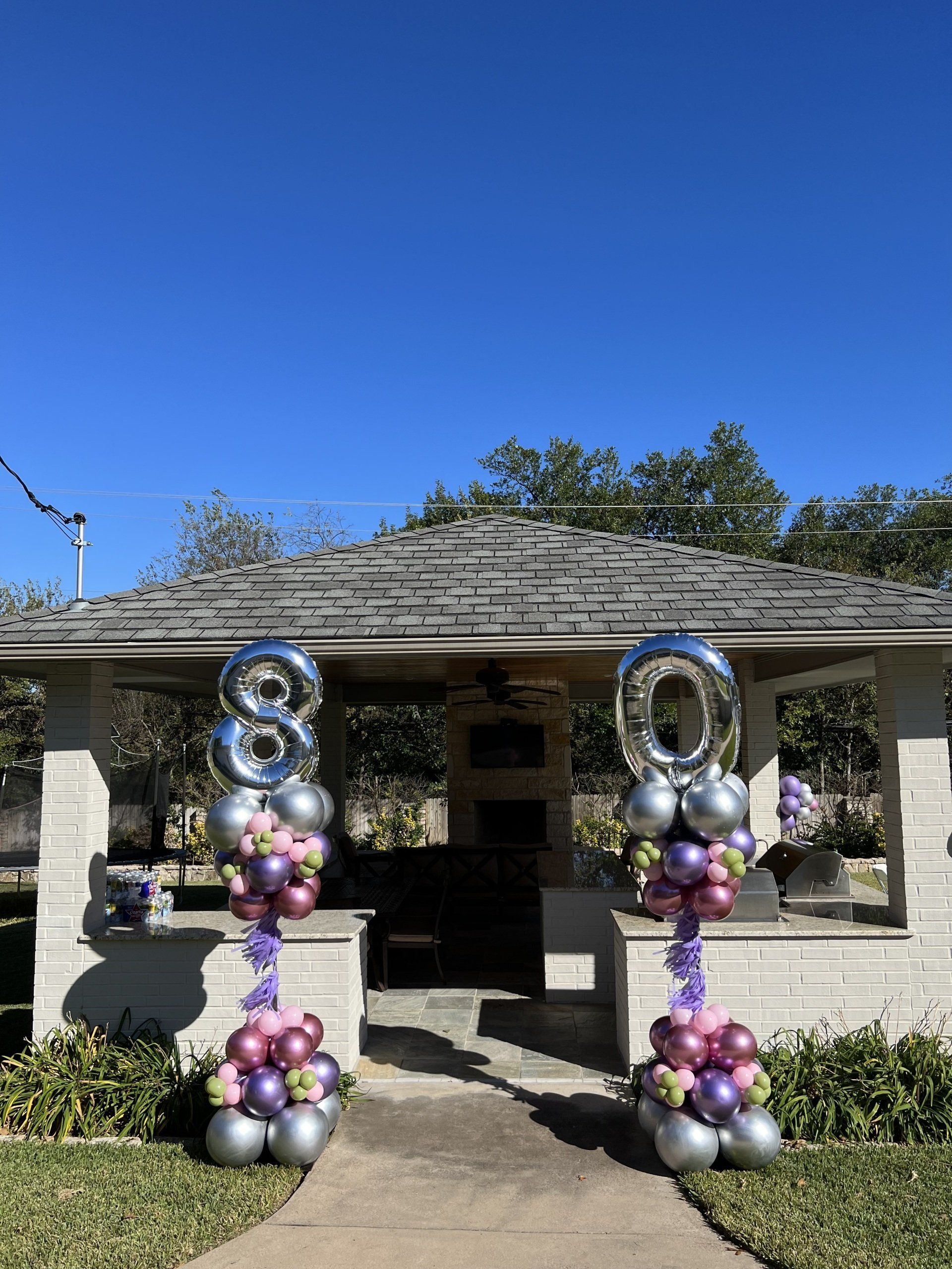 Two columns of balloons with numbers on them are in front of a gazebo.