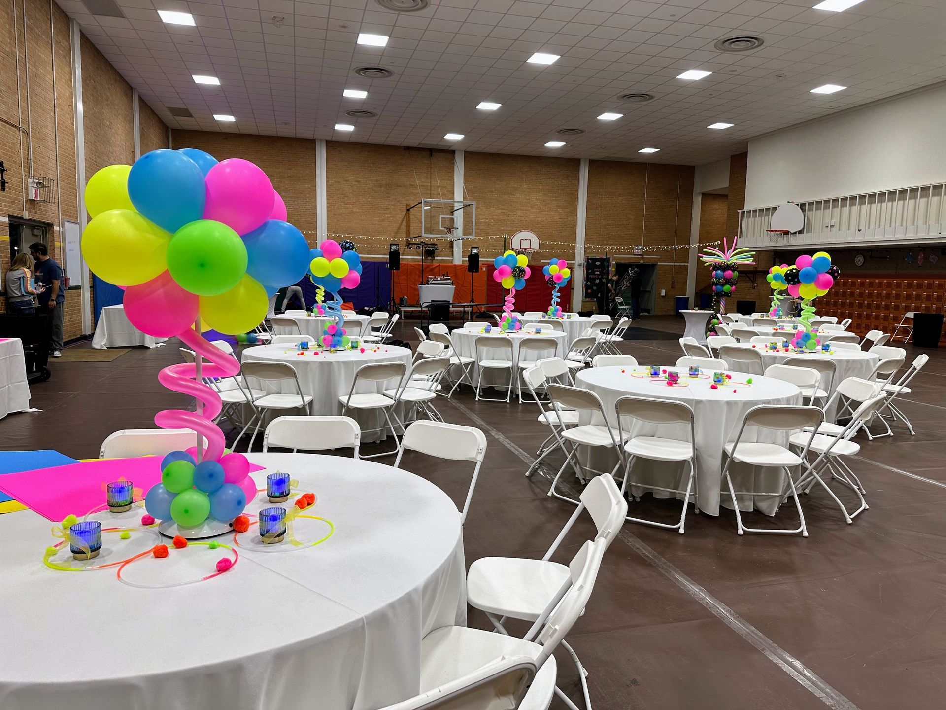 A large room filled with tables and chairs decorated with balloons.