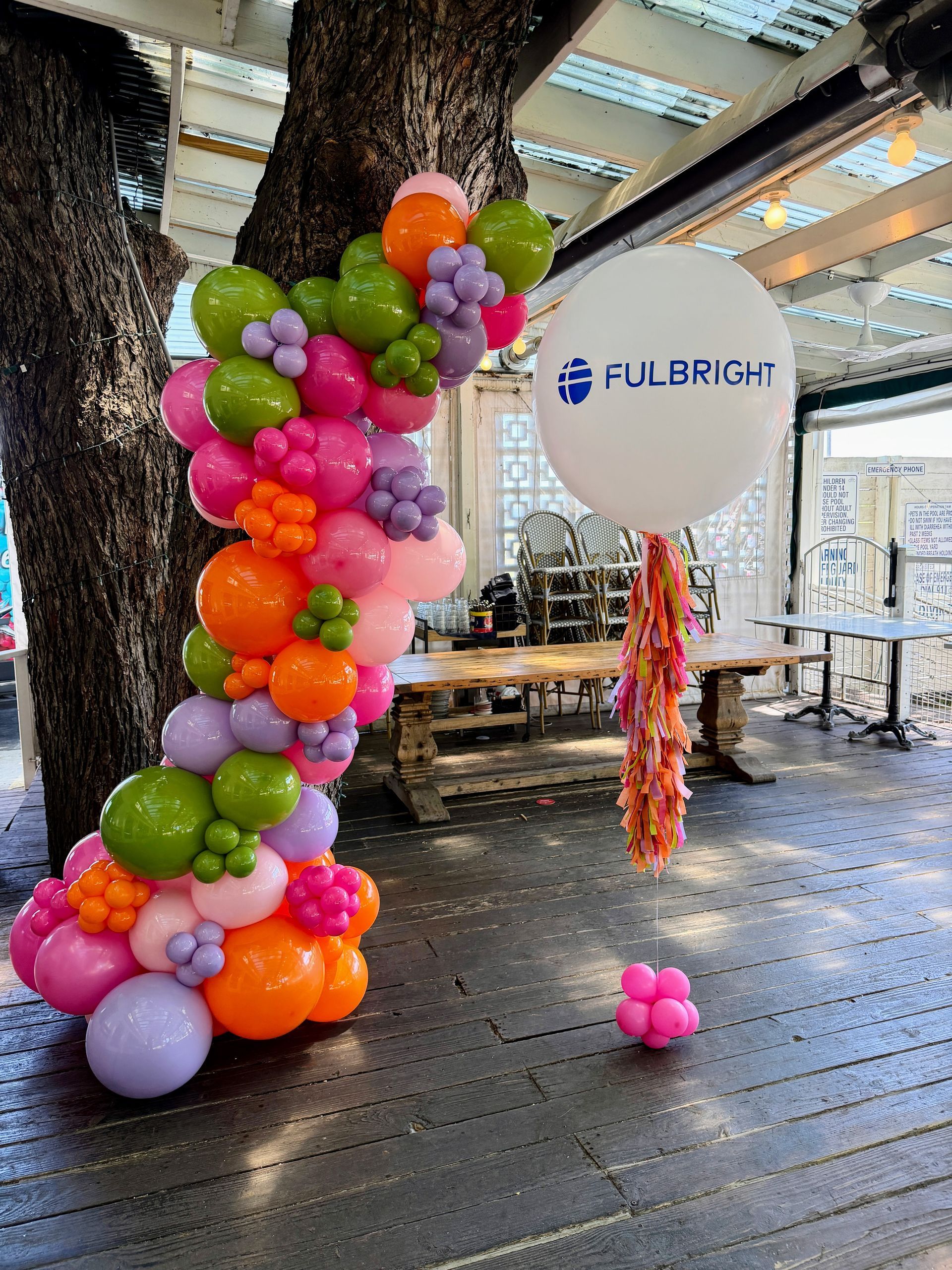A 12 foot floral themed balloon garland with green, pink, purple, and orange balloons.