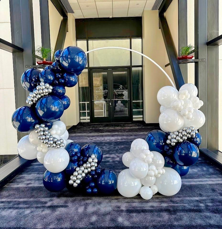 A bunch of blue and white balloons are sitting in front of a building