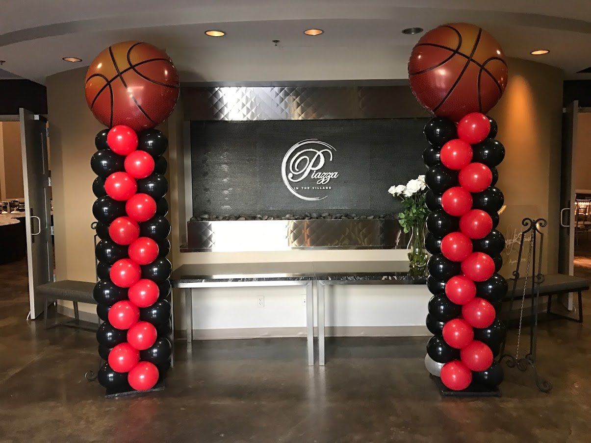 Two columns of red and black balloons with basketballs on top