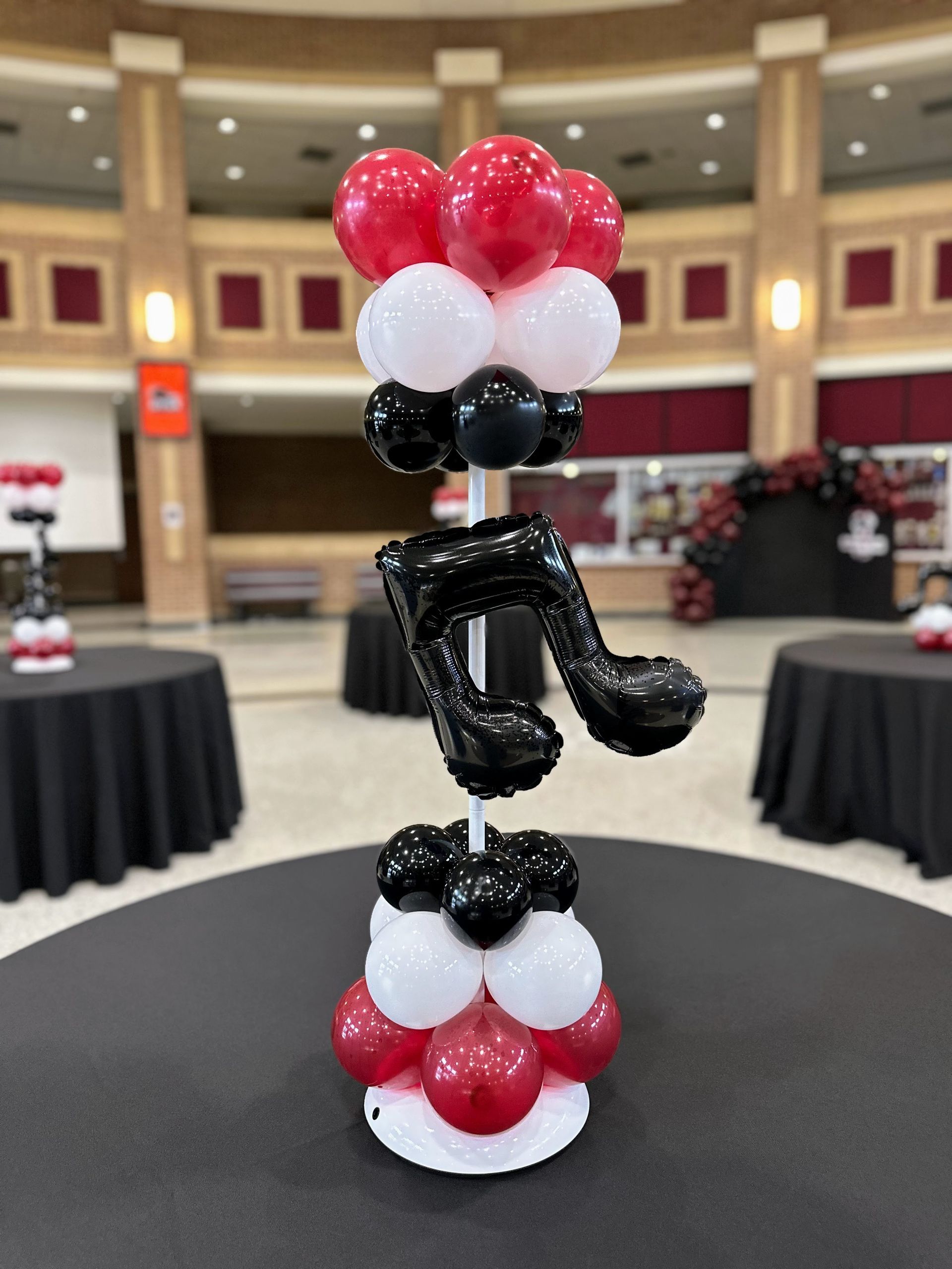 A red , white and black balloon tower with a music note on top