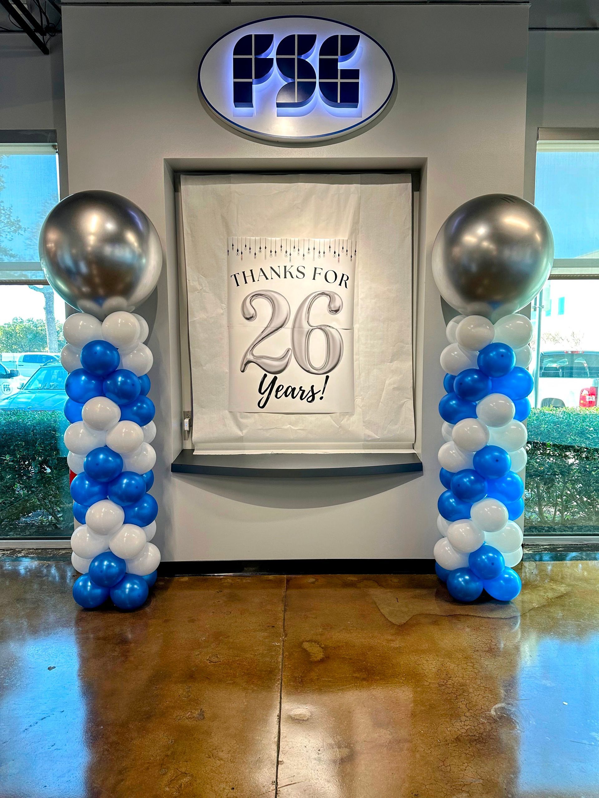 A room filled with blue and white balloons and a sign that says `` thanks for 26 years ''.