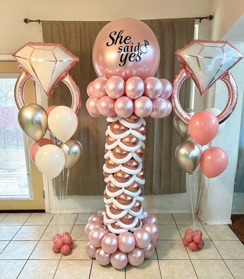 A pillar made of balloons with a balloon that says `` she said yes ''.