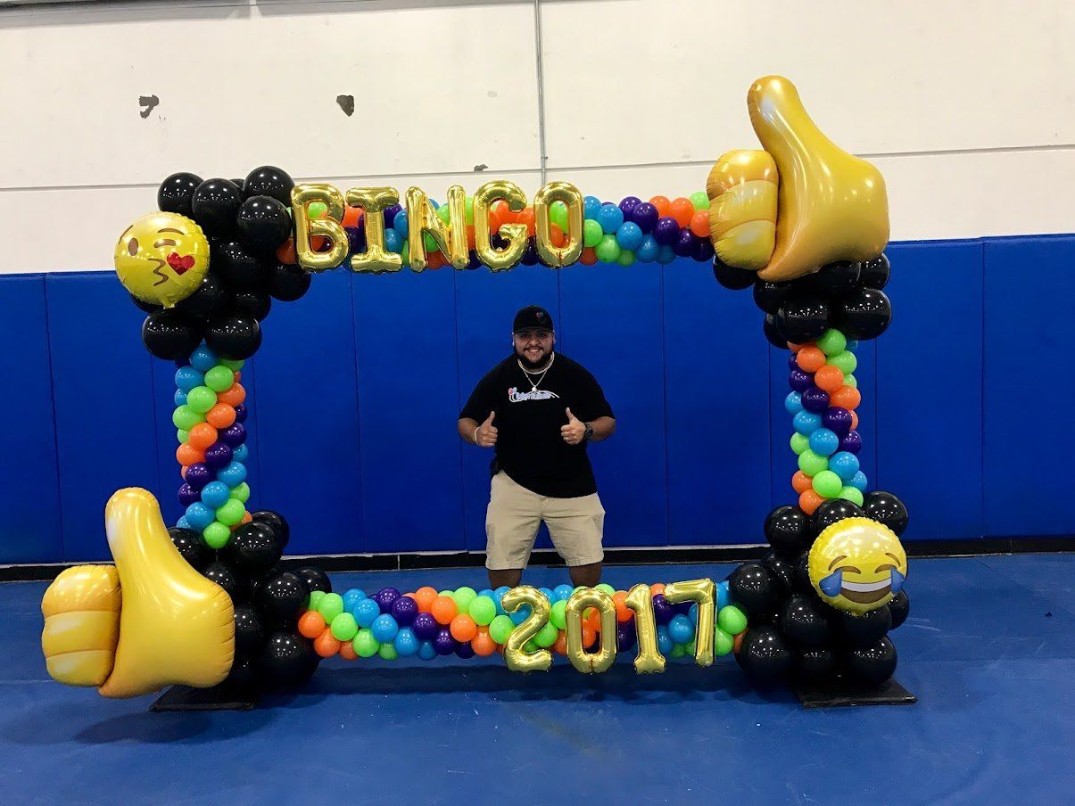 A man is standing in front of a balloon frame that says bingo 2017