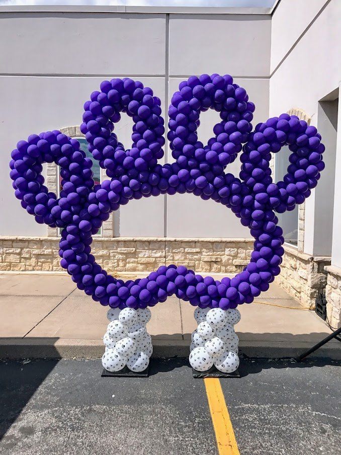 A paw print made out of purple and white balloons