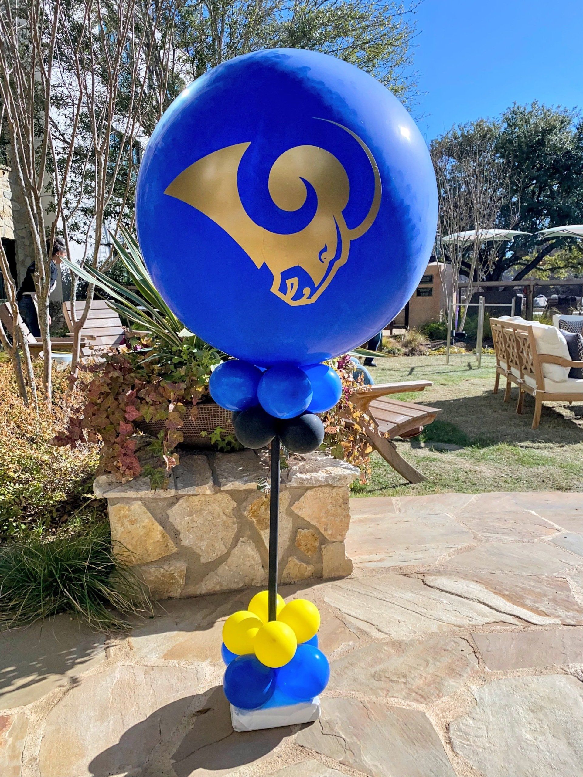 A blue rams balloon is sitting on top of a stack of balloons.