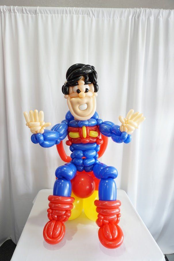 A balloon figure of superman is sitting on a table.