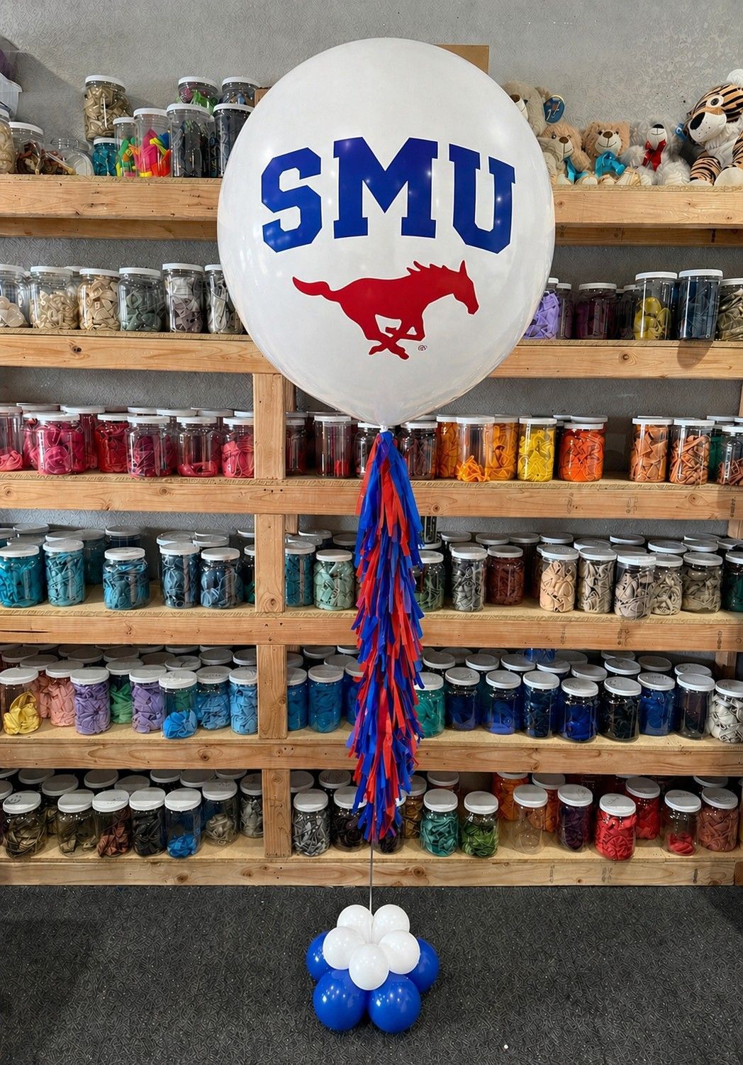 A jumbo helium balloon personalized with SMU College logo and color, with matching colored tassels..