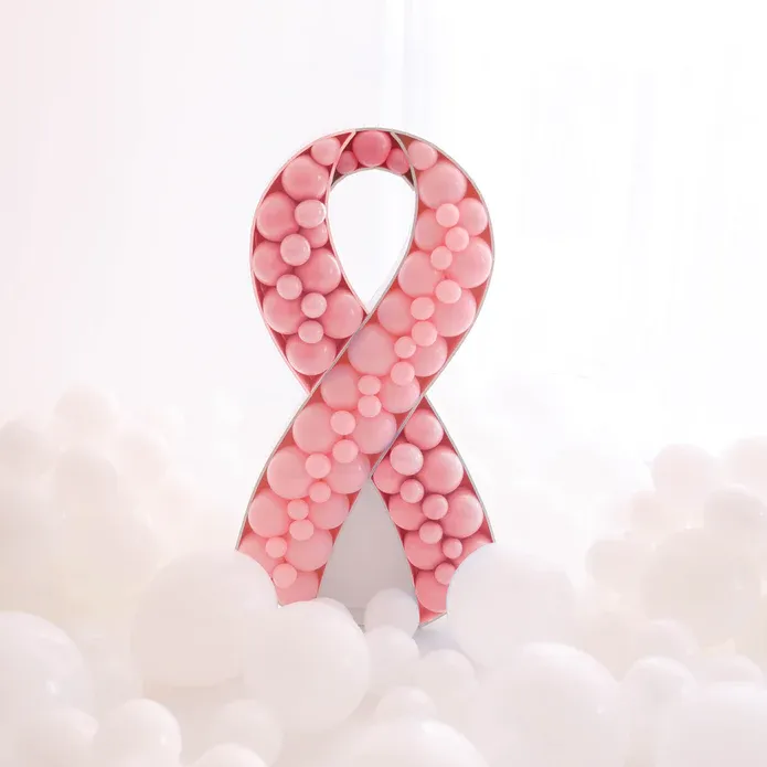A pink ribbon made of pink bubbles is surrounded by white clouds.