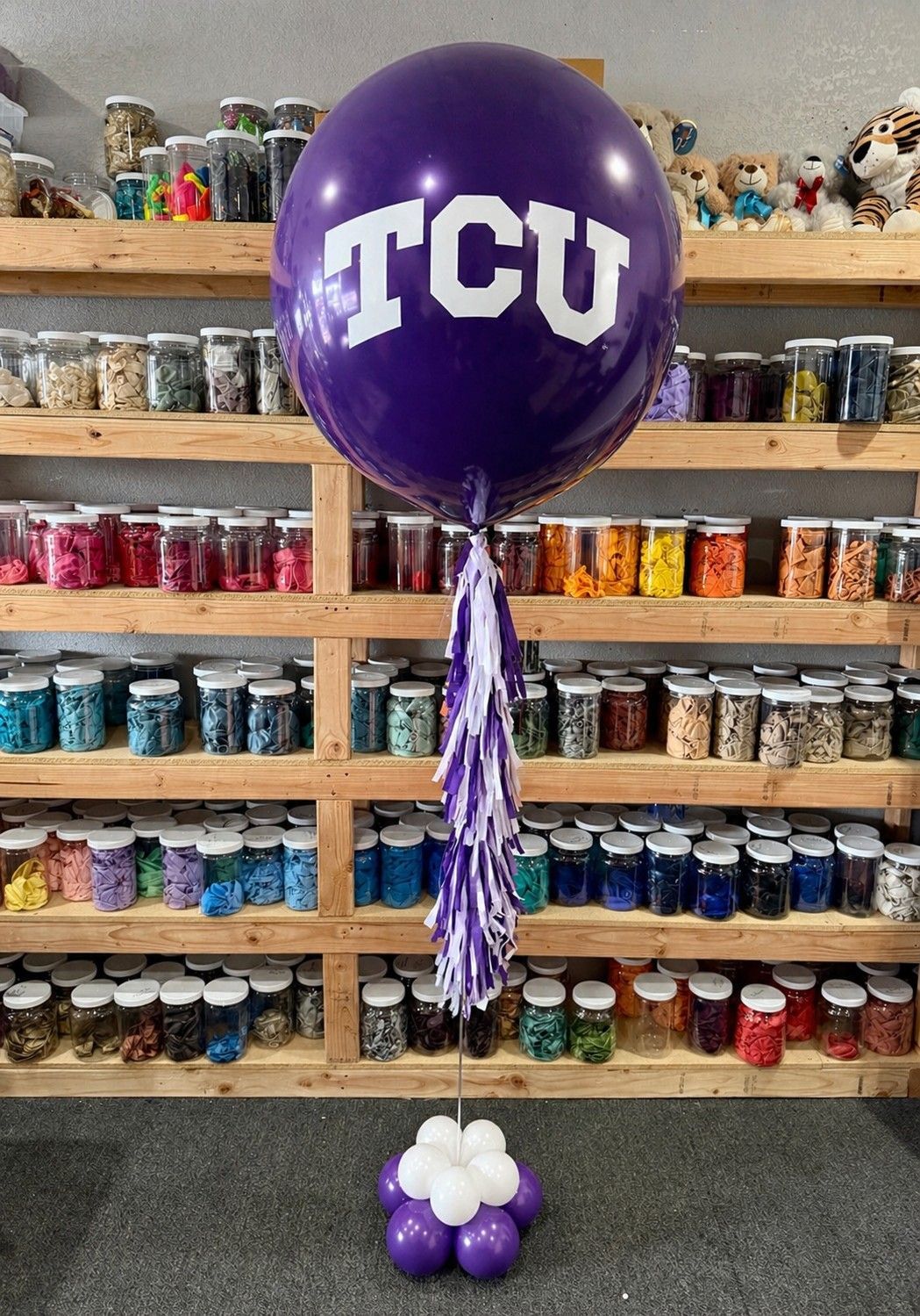A jumbo helium balloon personalized with TCU logo and color, with matching colored tassels..