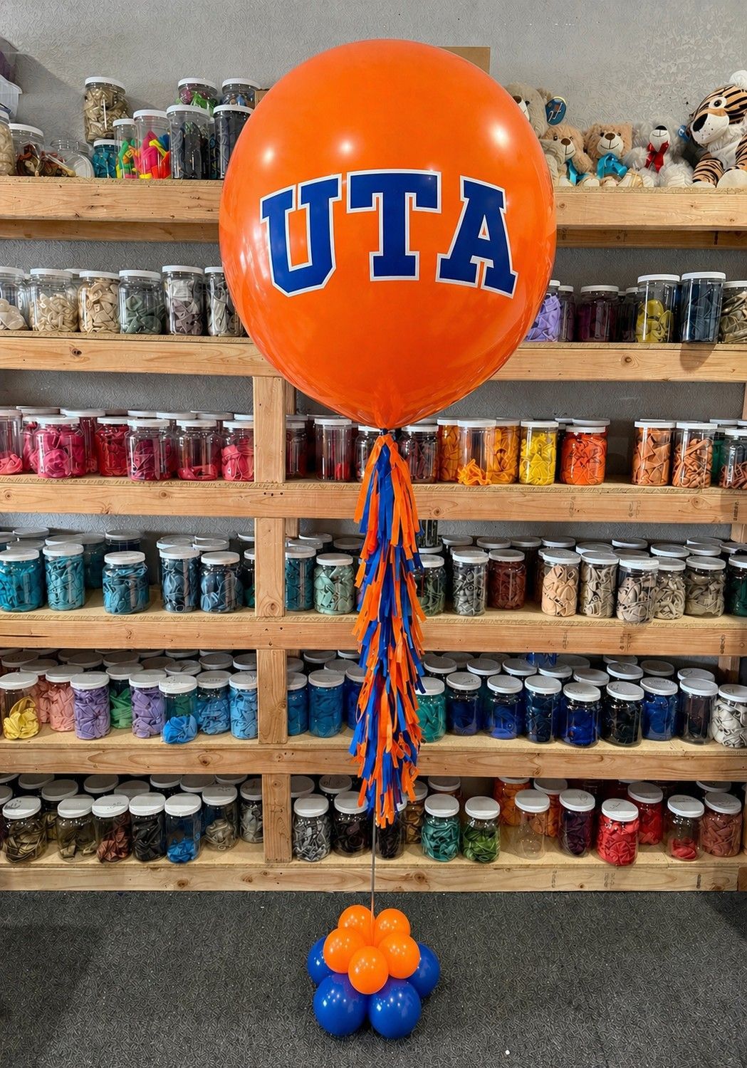 A jumbo helium balloon personalized with UTA College logo and color, with matching colored tassels..