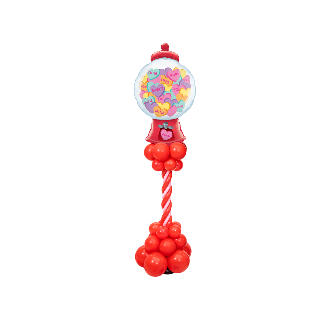 A gumball machine made out of balloons on a stand.