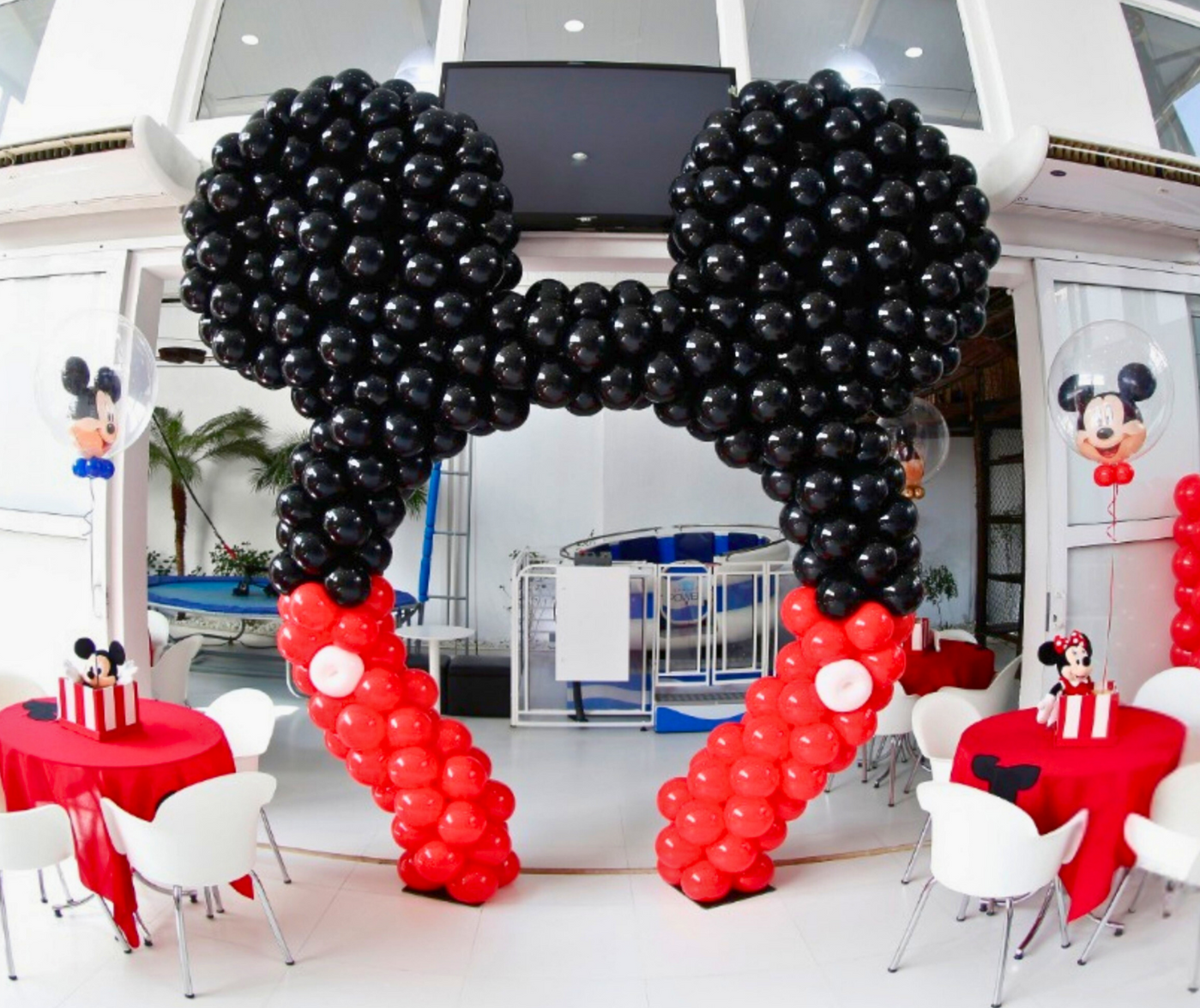Mickey mouse themed balloon arch in red, black and white balloons over a cake table