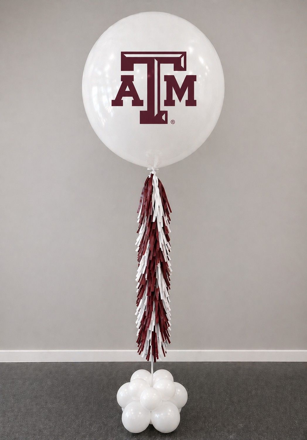 A jumbo helium balloon personalized with Texas a&m logo and color, with matching colored tassels..