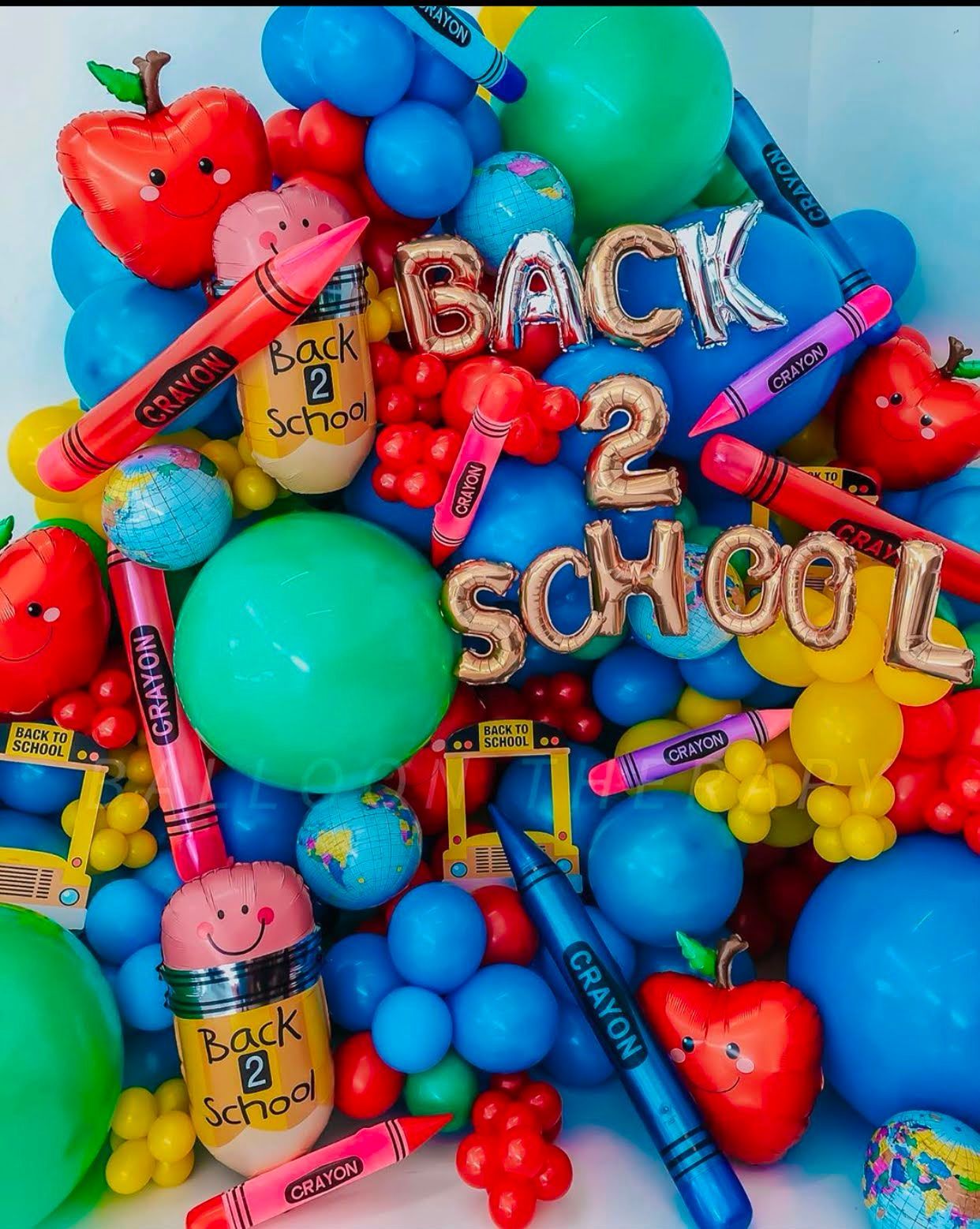 A back to school backdrop with red, blue, and colorful balloons with crayons and letter foils.